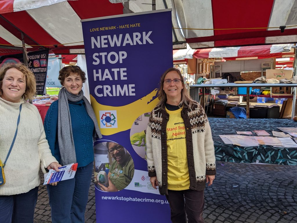 Three people in front of the Newark Stop Hate Crime market stall 2022